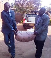 Hon. Kasaila (R) and Hon Lunguzi (L) helping each other to hand over a bag of maize to the sisters