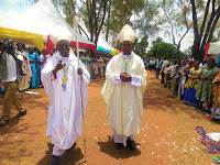 Bishop Kirabo (left holding a crosier)  with Rt. Rev. Lambert Bainomugisha,  the Auxiliary Bishop of Mbarara  Archdiocese during his ordination  ceremony as a bishop last year
