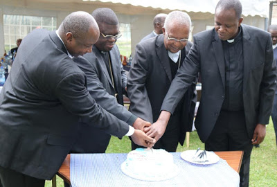 H.E. Cardinal Njue, AMECEA Chairman Bishop Kasonde, Fr. Lugonzo and Fr. Ndaga cutting farewell cake