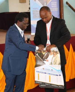 Rev. Dr. Jordan Nyenyember, (L) Coordinator AMECEA  Gaba Publication shares a copy of the 2019 calendar  with Director of Gaba Campus Dr. Simon Kang'ethe (R)