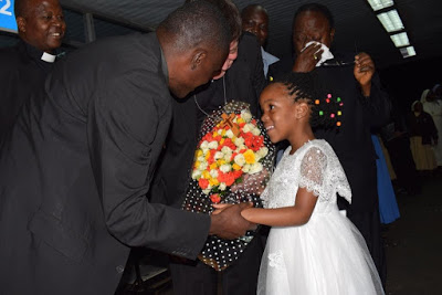A Little Girl presents a bouquet of flowers to João Cardinal Bráz de Aviz  on arrival at the Entebbe International Airport in Uganda.