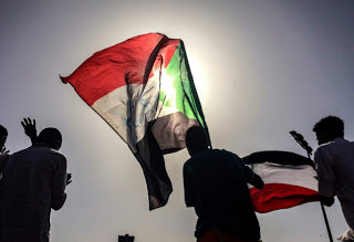 Sudanese demonstrators march with national flags as they gather during a rally demanding a civilian body to lead the transition to democracy, outside the army headquarters in the Sudanese capital Khartoum on Saturday, April 13, 2019.   The military overthrew President Omar al-Bashir on Thursday after almost four months of protests calling for an end to his nearly 30-year rule.  (AP Photo)