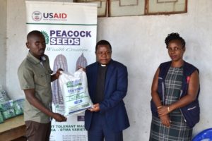 Sikwese (left) making a symbolic presentation of the maize seeds to Father Saindi as Sakunda-Ndhlovu looks on---Photo by Watipaso Mzungu, Nyasa Times