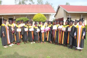 Graduands standing in a group while showing their certificates and transcripts after their first graduation at Asili Girls Vocational School in Lira city.