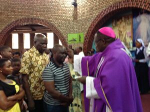 Bishop Kibira Giving Ash to Lt Joe Walusimbi the Kasese Resident District Commissioner