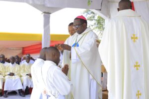 Bishop Kibira laying hands on Now Fr Modesto and Loti