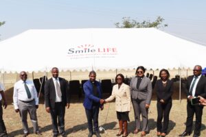 Rev. Fr. Dr. Sumani shakes hands with Smile Deputy CEO Mangwana after the handover of the tent