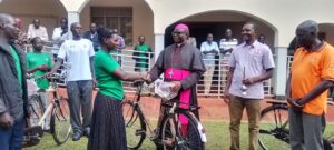 Rt Rev Sanctus Lino Wanok bishop of Lira handing over bicycle to a beneficiary